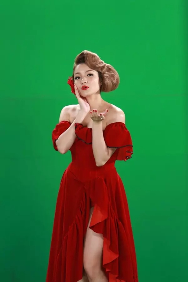 Thuỷ Top đội tóc giả, diện váy đỏ "nhái" hình ảnh kinh ảnh của biểu tượng gợi cảm khi tham gia gameshow Hoán đổi 2015.

