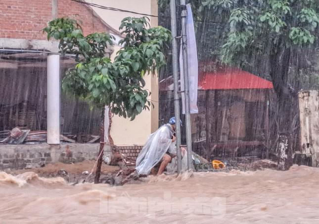 Một người đàn ông bị mắc kẹt giữa dòng nước dữ trên đường Hàn Mặc Tử, phường Ghềnh Ráng. Ảnh: Trương Định