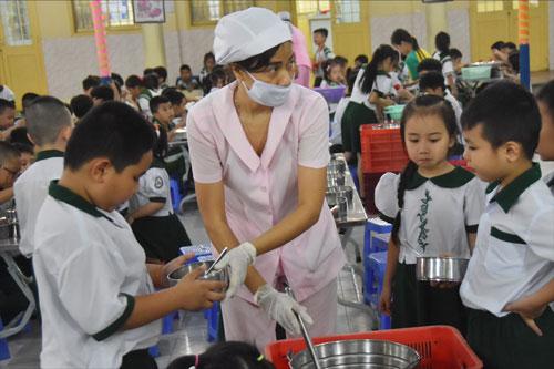 Học sinh tại một trường tiểu học ở quận 1, TP HCM nhận suất ăn bán trú Ảnh: TẤN THẠNH