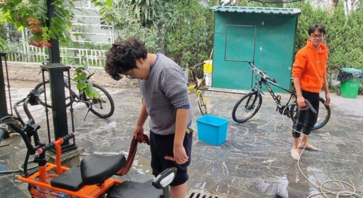 Bi Béo và anh trai Minh Bủm ngày nghỉ cũng phải lao động. 2 cậu bé rửa "khối tài sản" của gia đình gồm 1 xe máy, 1 xe điện và 5 xe đạp.