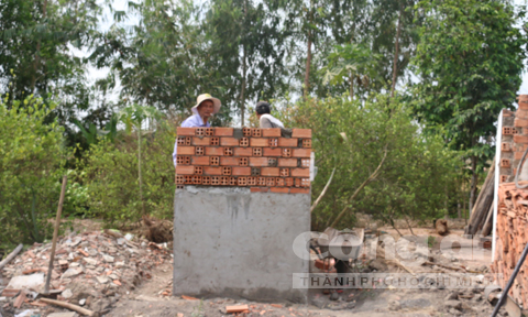 Các thợ hồ đang hoàn thiện ngôi mộ mới của chị Lan