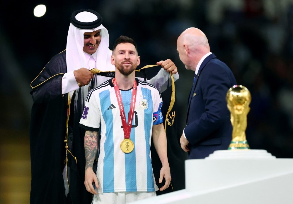 Tiểu vương Qatar Sheik Tamim bin Hamad Al Thani khoác chiếc áo choàng đen cho Messi trước màn nâng cúp vô địch. Ảnh: Twitter