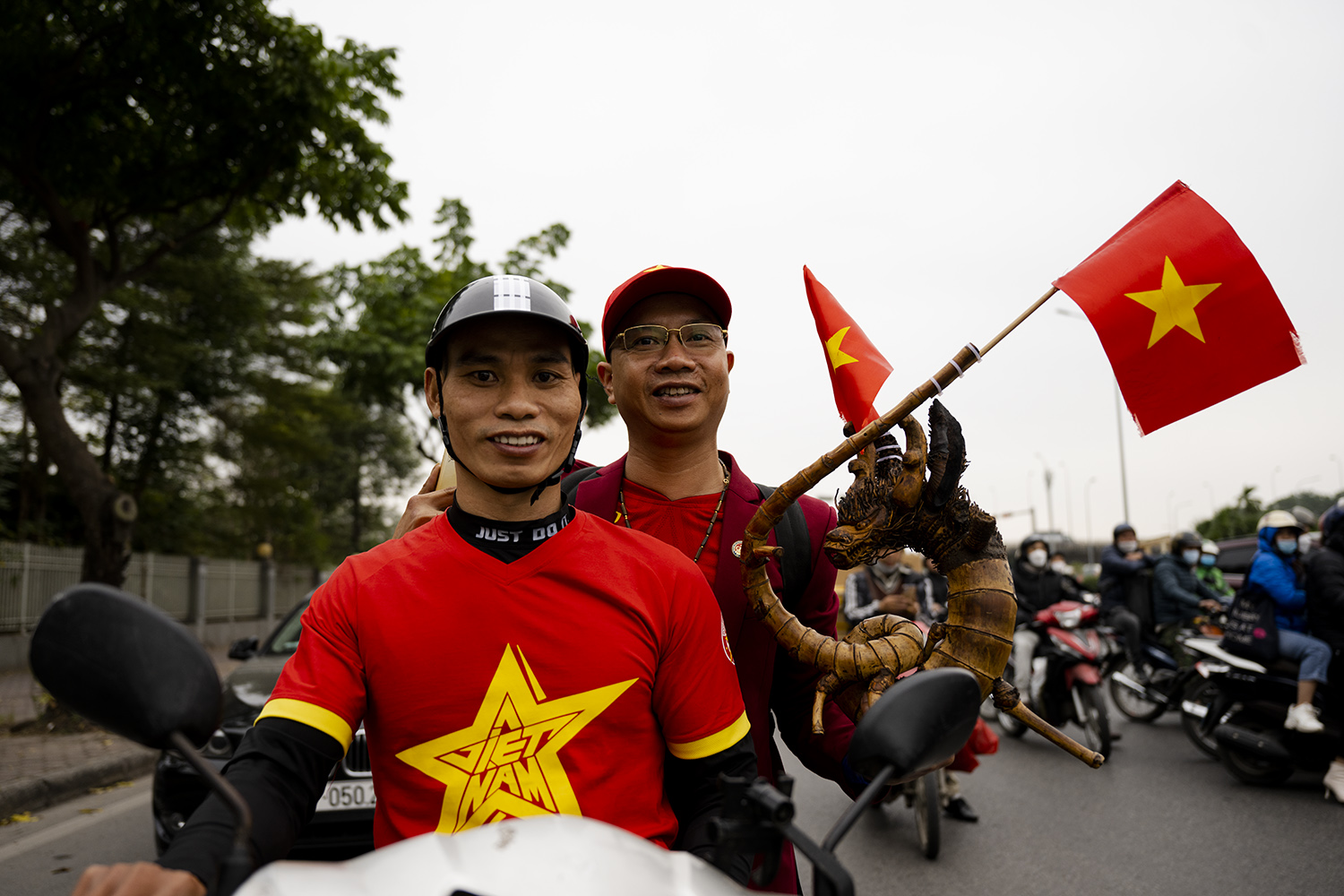 Hai cổng động viên đi xe máy từ Phủ Lý (Hà Nam) đến Hà Nội, mang theo hình con rồng bằng rễ tre, với hi vọng sẽ mang lại may mắn cho đội tuyển Việt Nam trong tối nay.