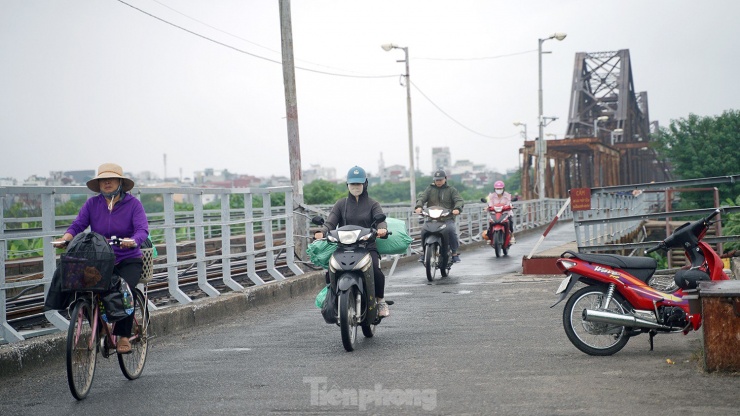 Người dân đi lại trên cầu Long Biên trong mưa nhỏ và gió thổi mạnh.