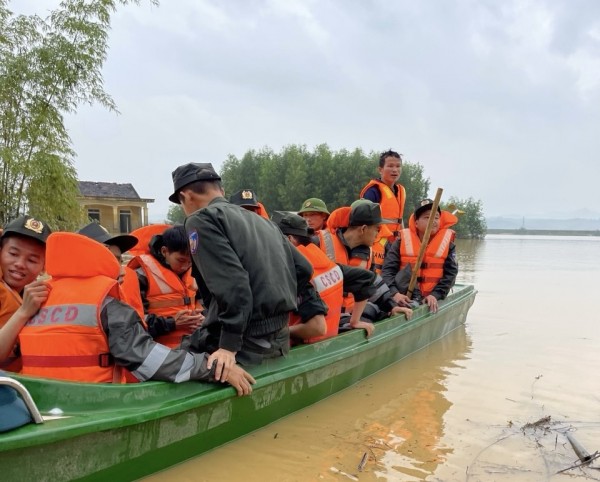 Lực lượng cảnh sát cơ động dùng xuồng vượt nước lũ vào địa bàn giúp nhân dân.