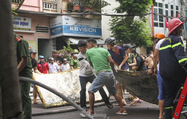 Người dân hỗ trợ di chuyển những tấm nệm bên trong căn nhà bị cháy ra ngoài. Ảnh: Trương Định