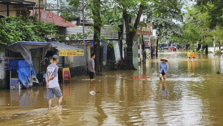 Người dân bì bõm trong dòng nước bạc khi nước lũ dần rút.