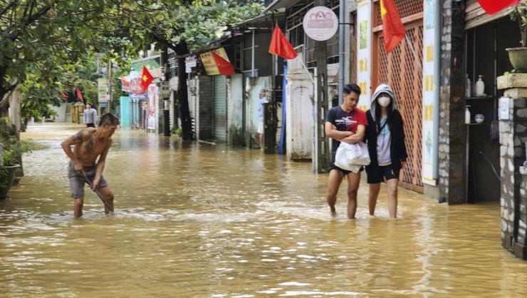 Người dân tranh thủ cạo lớp bùn đất trên mặt đường.