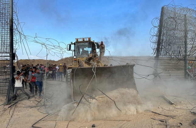 Lực lượng Hamas dùng xe ủi húc đổ hàng rào của Israel trong cuộc tấn công ngày 7/10. (Ảnh: Reuters)