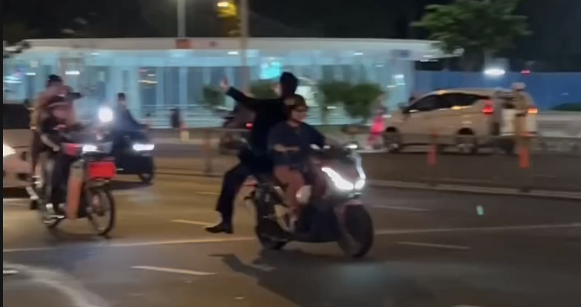 Hai xe máy chở người ngồi phía sau không đội mũ bảo hiểm và đứng trên yên xe (ảnh chụp từ clip)