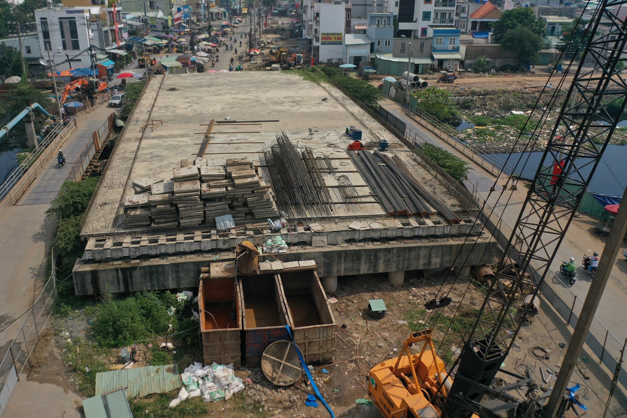 Hiện tại trên mặt cầu đơn vị thi công đang tập kết sắt thép, gạch đá để xây dựng lại. Bên trong rào chắn máy móc được huy động để tiếp tục công trình dang dở trong cuối năm nay. Theo Sở GTVT TP.HCM, các hạng mục thi công gồm: mố cầu, tường chắn, bản mặt cầu.