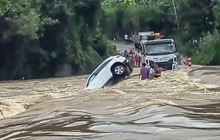 Xe ô tô bị nước lũ cuốn trôi, hai người bên trong may mắn thoát nạn. Ảnh: TL