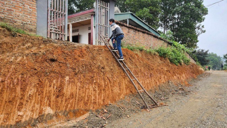 Dân bắc thang trèo vào nhà khi đơn vị thi công hạ cao trình dự án đường liên vùng 1.900 tỉ đồng ở Phú Thọ. Ảnh: XUÂN NGUYỄN.