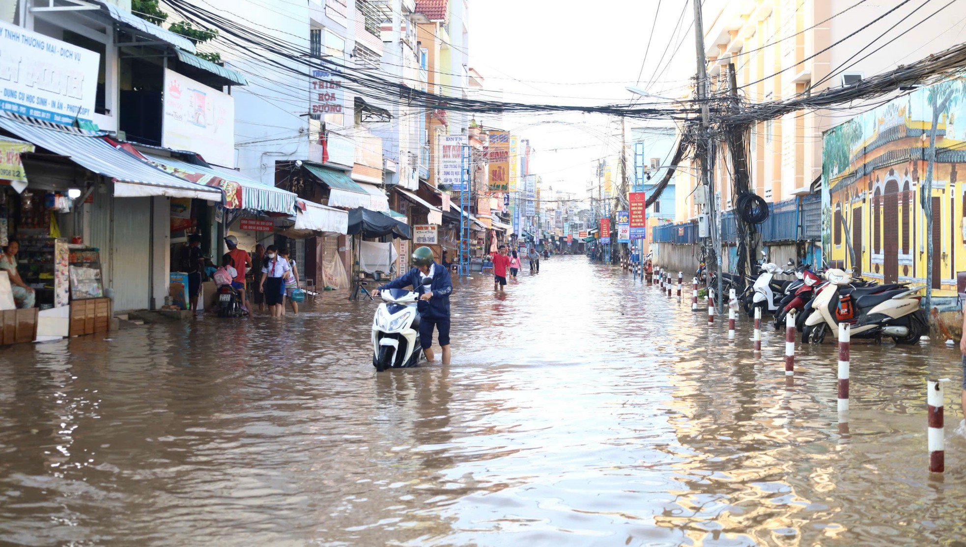 Người dân đi làm, học sinh đến trường vất vả qua những con đường ngập nước.