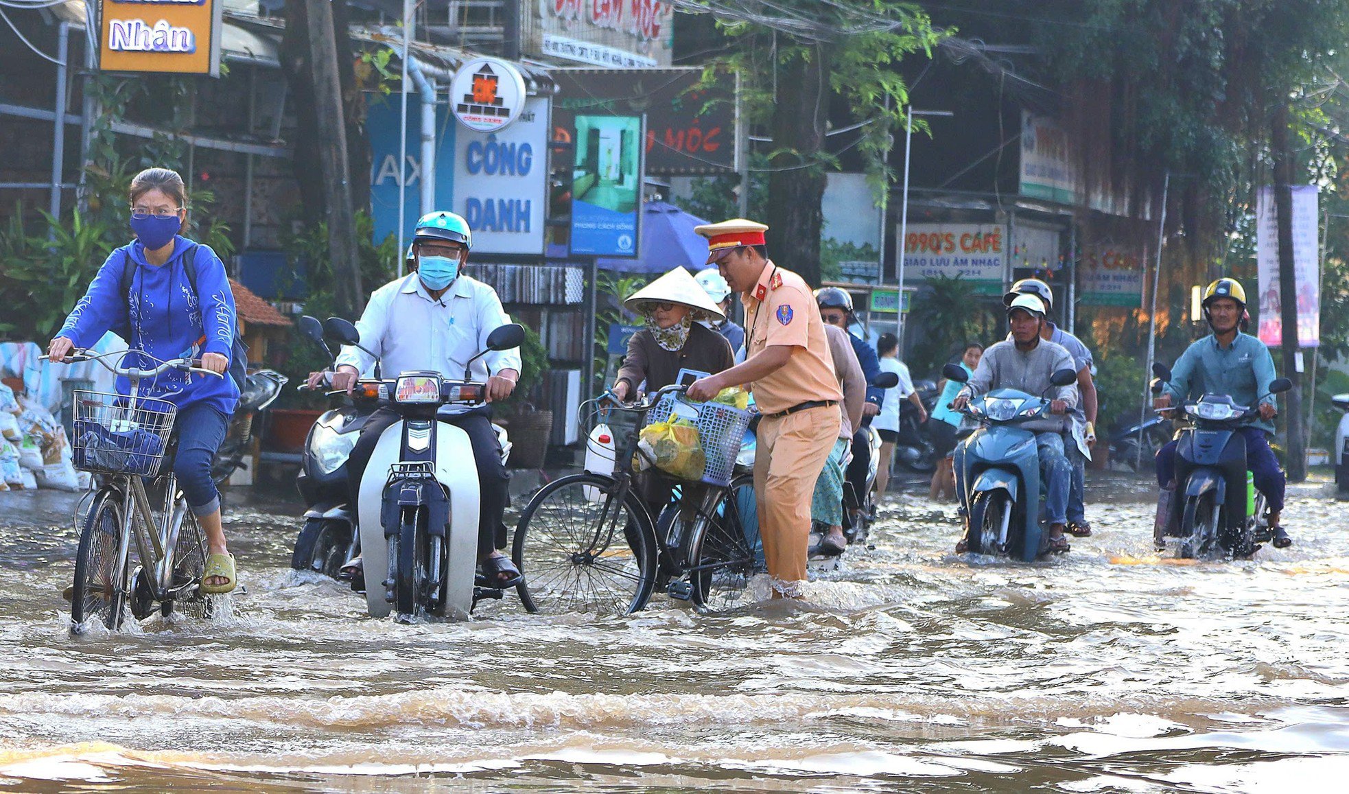 Lực lượng công an, đoàn viên thanh niên giúp đỡ người dân đi qua vùng ngập sâu.