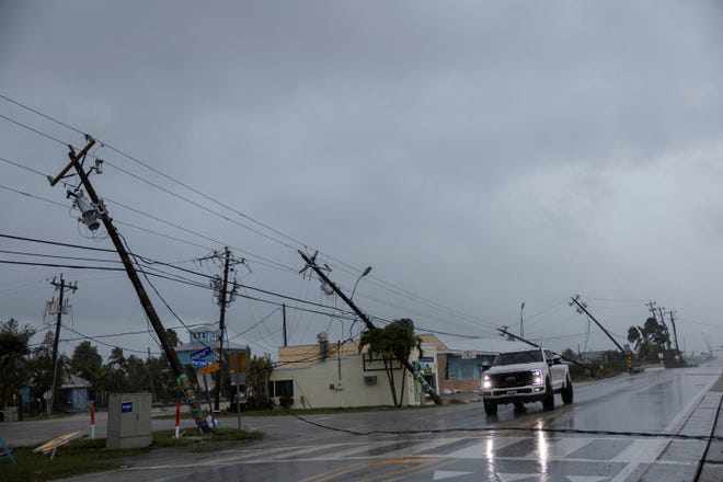 Hàng loạt cột điện nghiêng ngả khi bão đổ bộ ở Fort Myers, bang Florida. Ảnh: Reuters