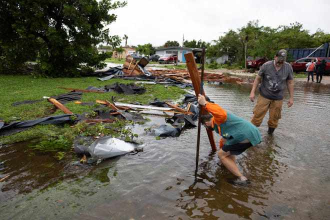 Người dân thu dọn đống đổ nát trên đường ở Fort Myers, bang Florida. Ảnh: Reuters