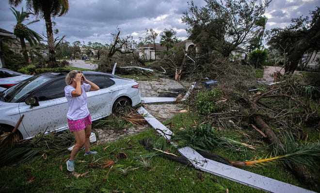 Một phụ nữ bị sốc trước cảnh ngôi nhà bị hư hại sau khi bão đi qua. Ảnh: USA Today