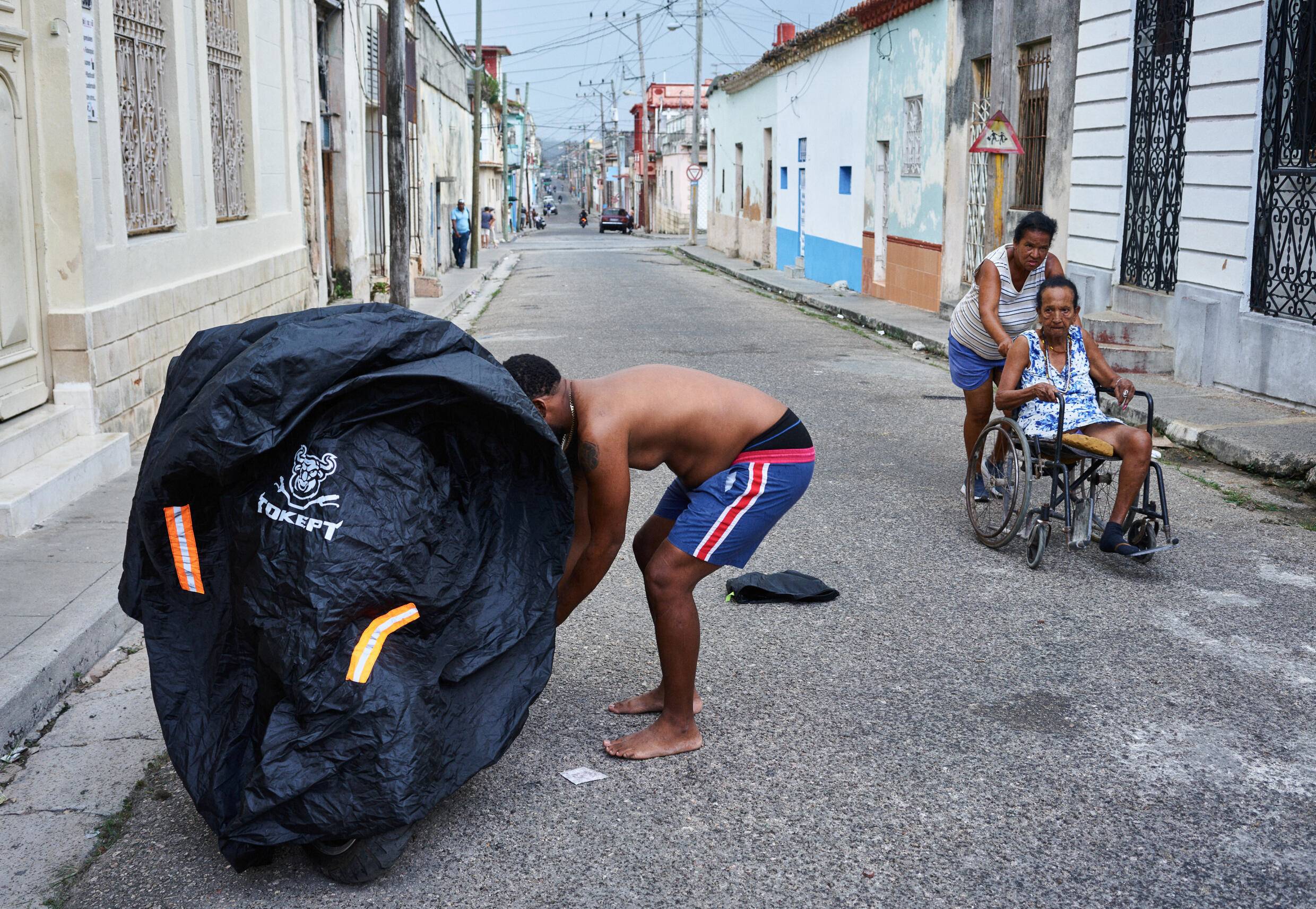 Người đàn ông ở Cuba bọc và khóa chiếc xe máy điện, do không có điện sử dụng (ảnh: AFP)