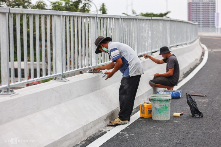 Trước ngày thông xe các hạng mục đều hoàn thiện, chỉ còn một vài công nhân dặm vá lại lan can và vệ sinh trên cầu.