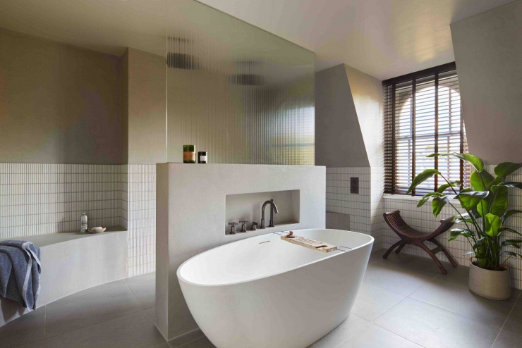 Phòng tắm chính nổi bật với bồn tắm đặt giữa không gian và vách kính mờ phân khu nhẹ nhàng. Giải pháp này giúp phòng tắm vừa riêng tư, vừa giữ được ánh sáng tự nhiên và sự thông thoáng