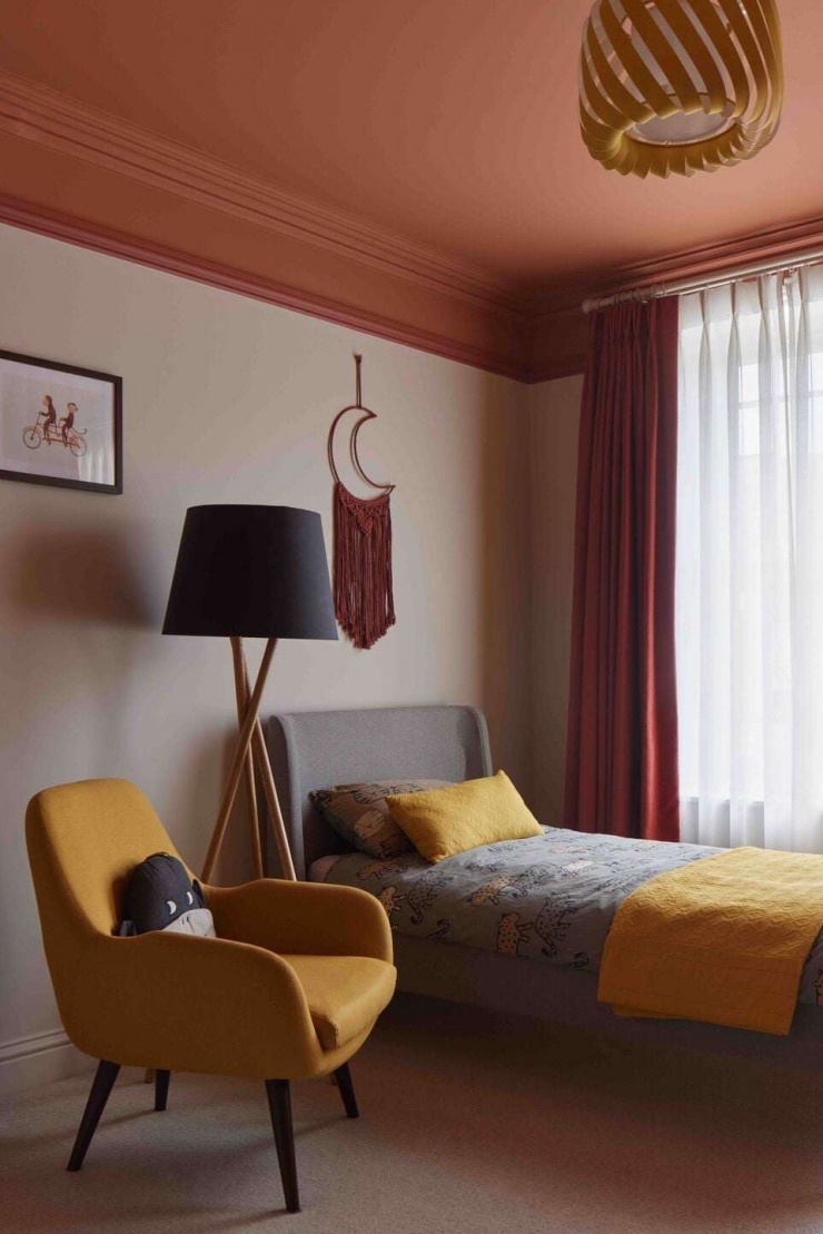Phòng ngủ trẻ em sử dụng bảng màu ấm với trần sơn màu đất và rèm vải mềm. Cách phối màu tạo cảm giác gần gũi, giúp không gian vừa sinh động vừa không quá kích thích thị giác