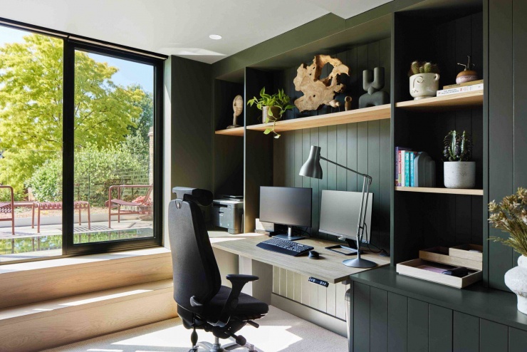 Phòng làm việc nhìn thẳng ra khu vườn phía sau qua cửa kính lớn, ngập tràn ánh sáng ban ngày. Hệ tủ âm tường và bàn làm việc liền khối giúp không gian gọn gàng, phù hợp cho làm việc tại nhà lâu dài